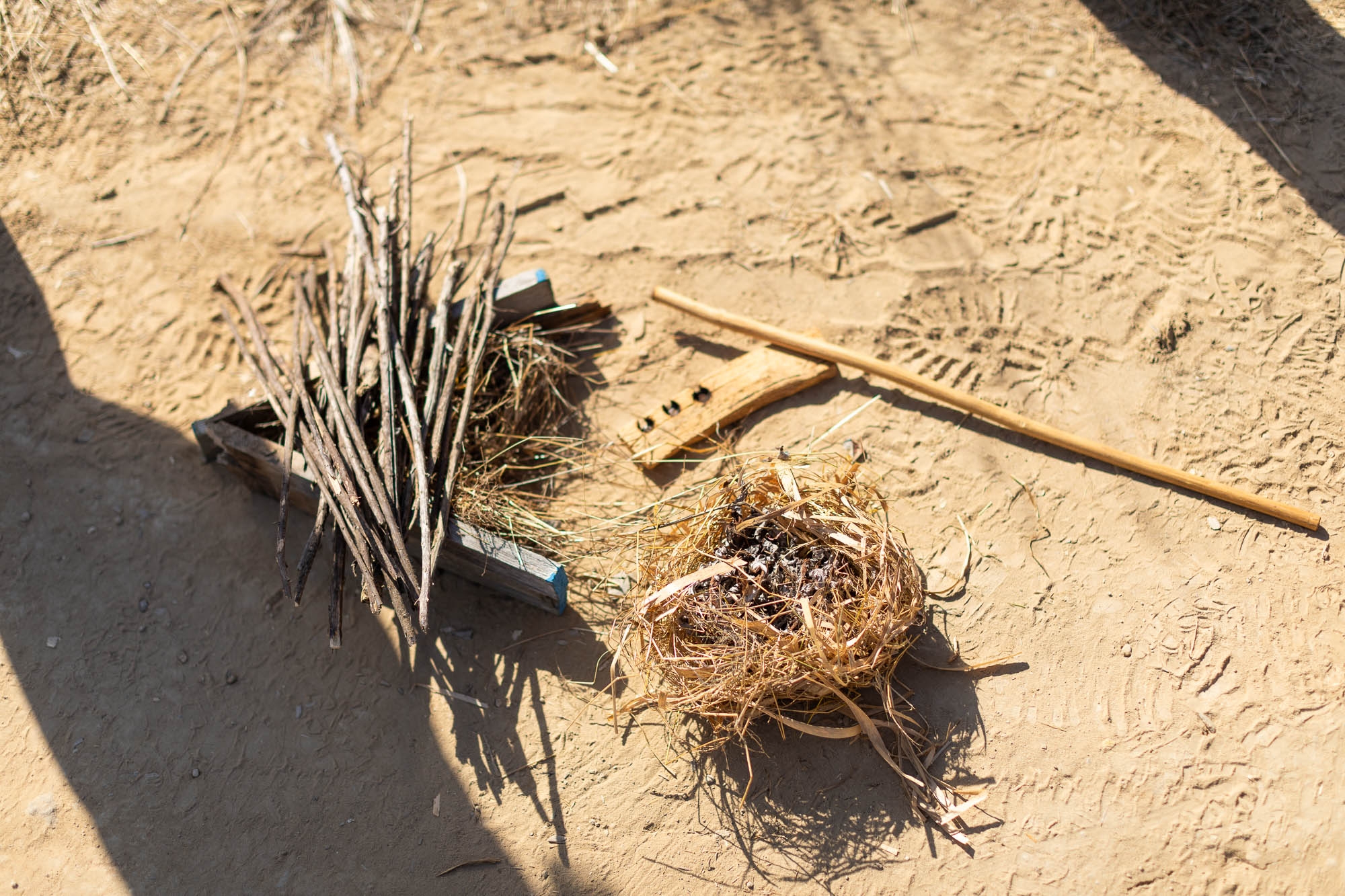 An elderberry drill, hearth of California buckeye wood, mugwort tinder, and a few other sticks arranged on the ground.