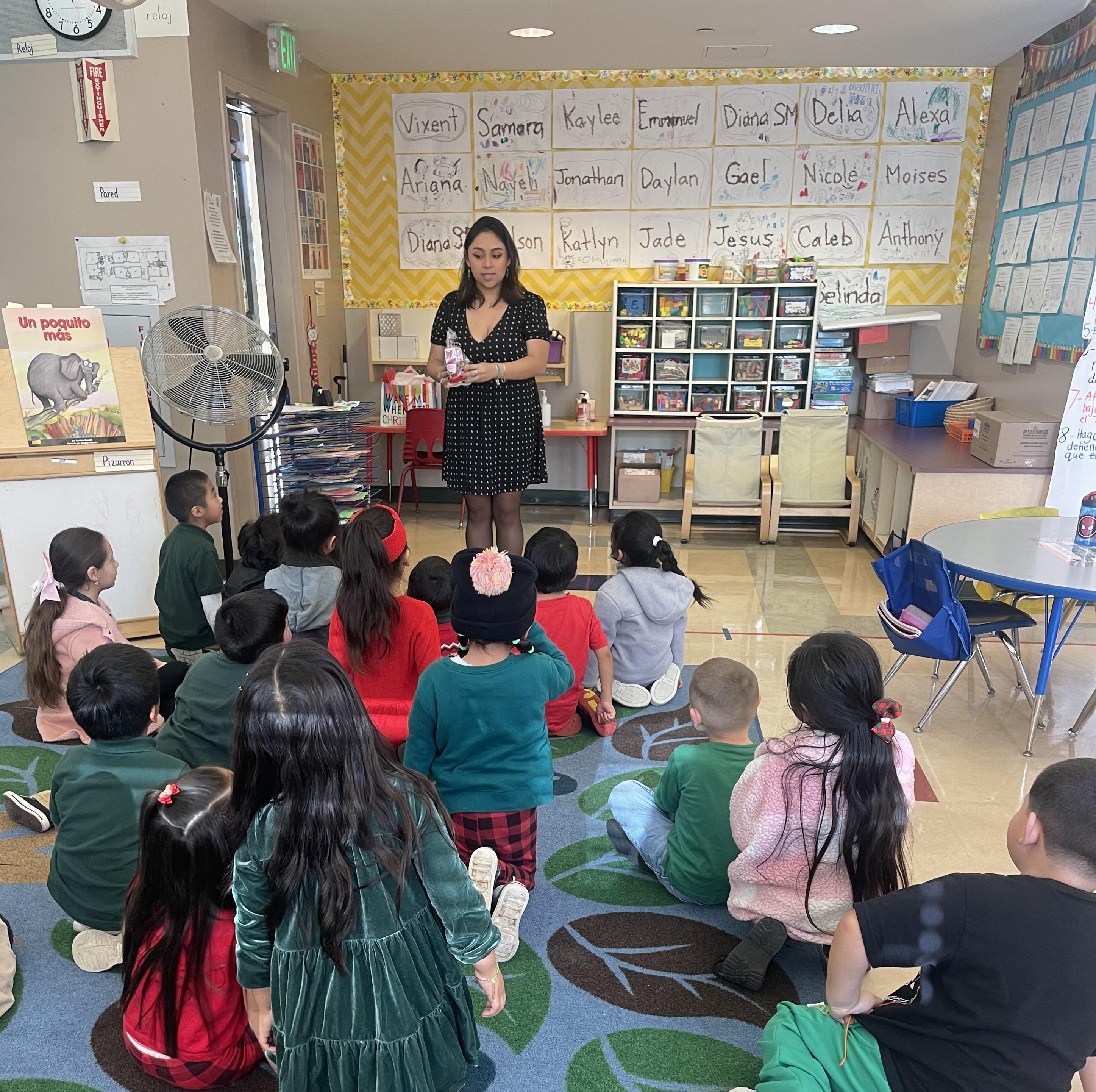 A young Latina woman teaches a class of kindergarteners