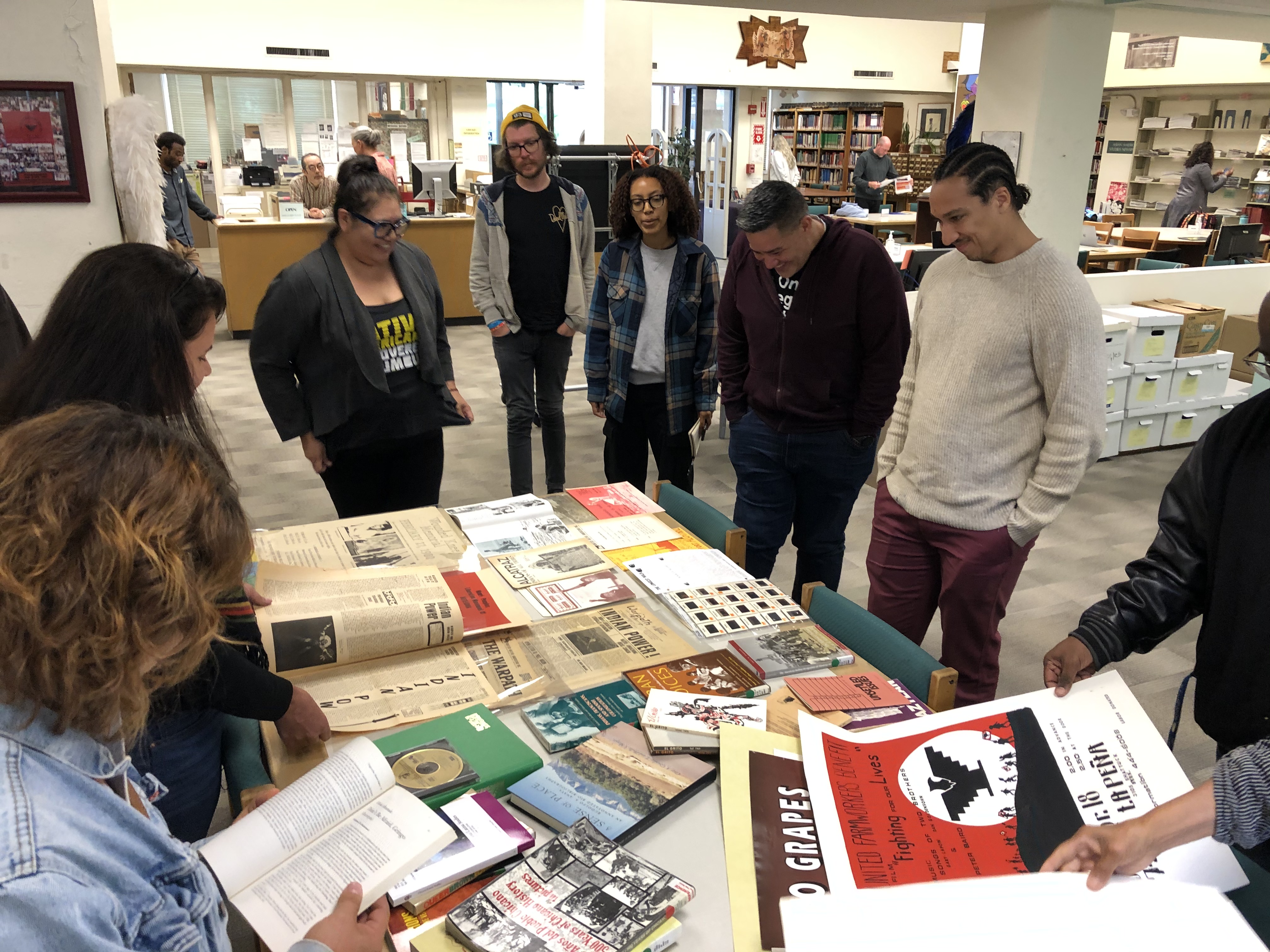 A diverse group of teachers look at a table of materials from UC Berkeley's ethnic studies archive