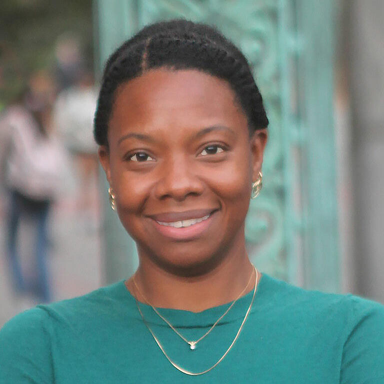 African American woman in teal shirt smiling at camera