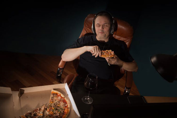 Man in chair eating pizza at night