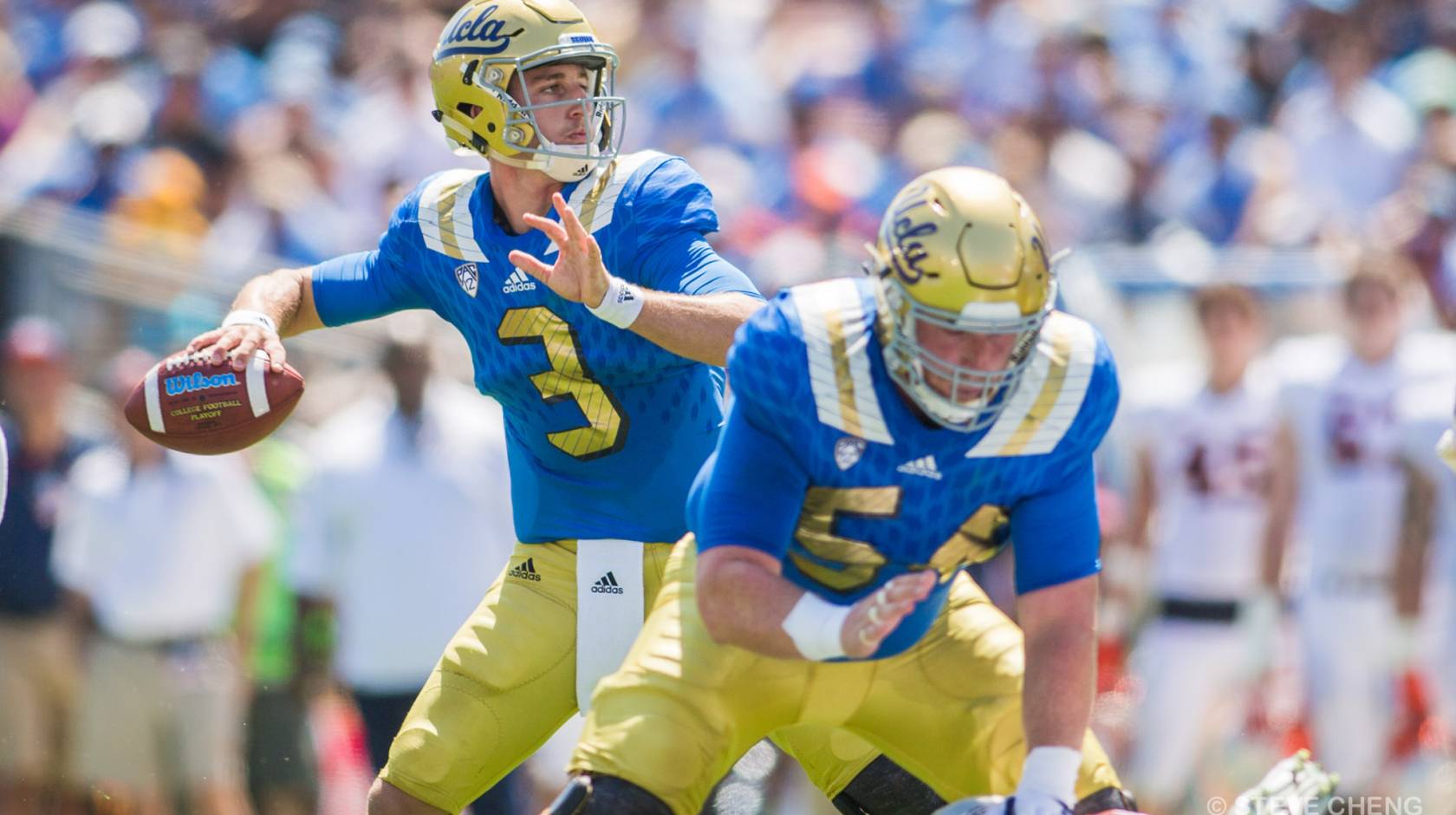 A quarterback in UCLA colors, blue and gold, angles his arm for a pass, while a center, the Niners' Jake Brendel, protects him