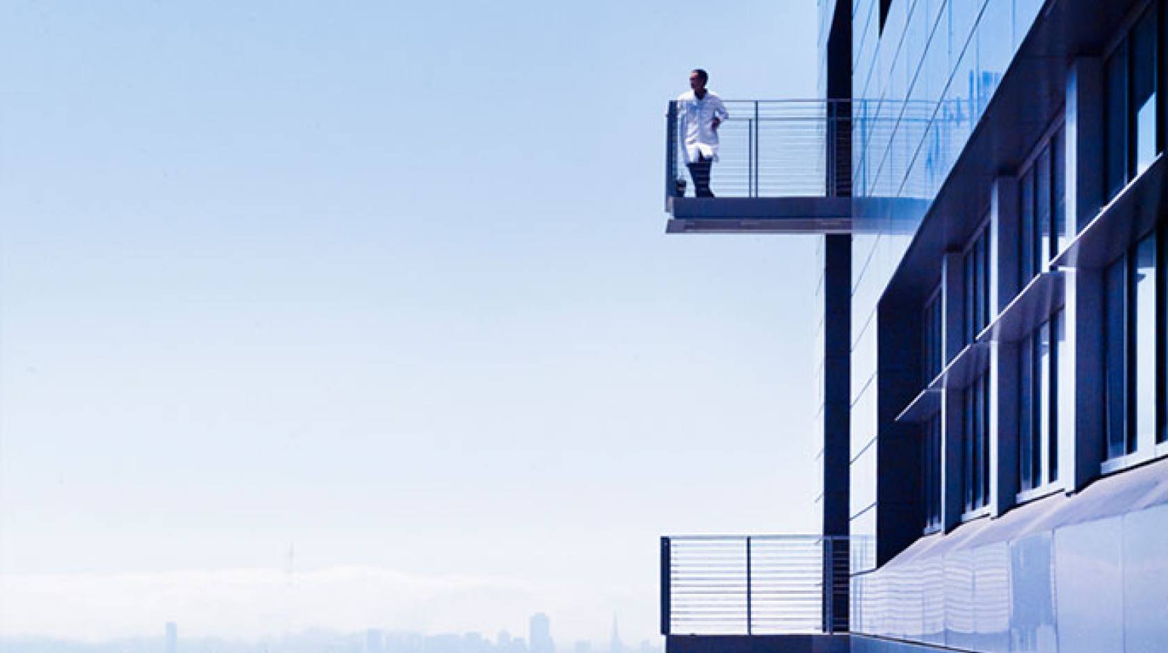 Researcher on a balcony with San Francisco skyline behind