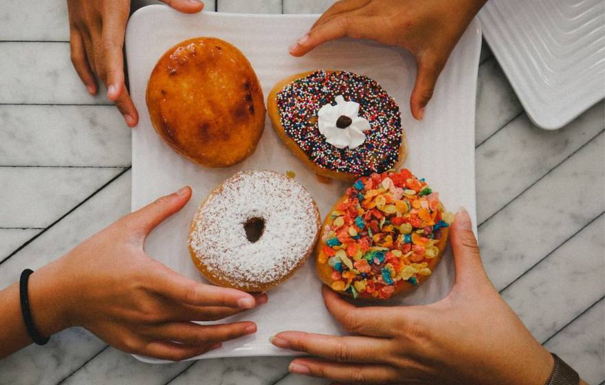 Multiple hands reaching for donuts
