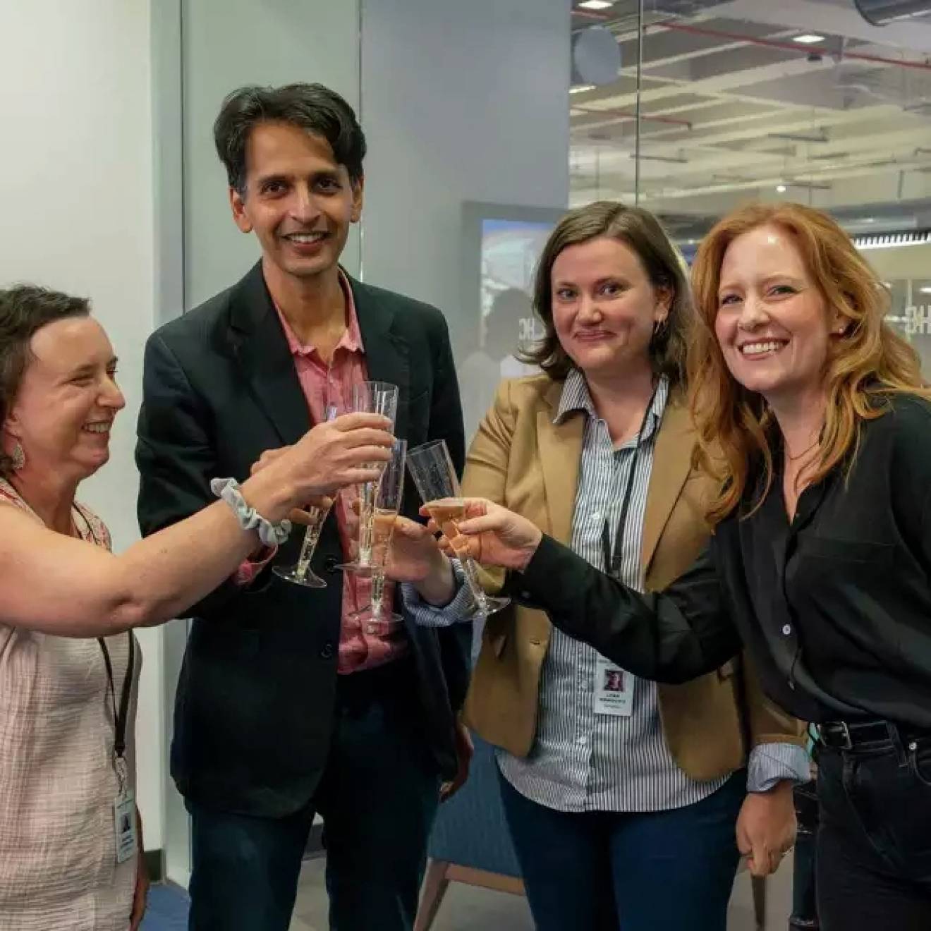 Houston Chronicle wins Pulitzer Four people in a newsroom do a champagne toast, smiling at the camera
