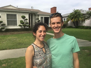 Stosh Ozog and Miriam Rubensen stand in front of a house.