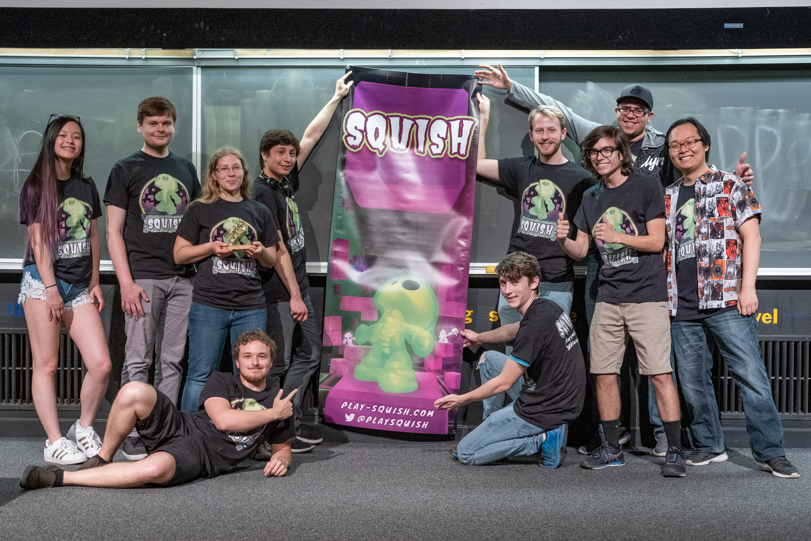 Squish team surrounds a banner that says Squish and shows one of their little green skeleton-like characters