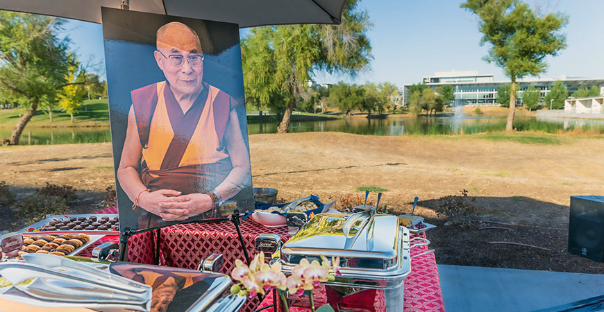 Outdoor gathering with photo of Dalai Lama as a reception for the event