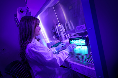 Woman working with UV-emitting machine in a lab