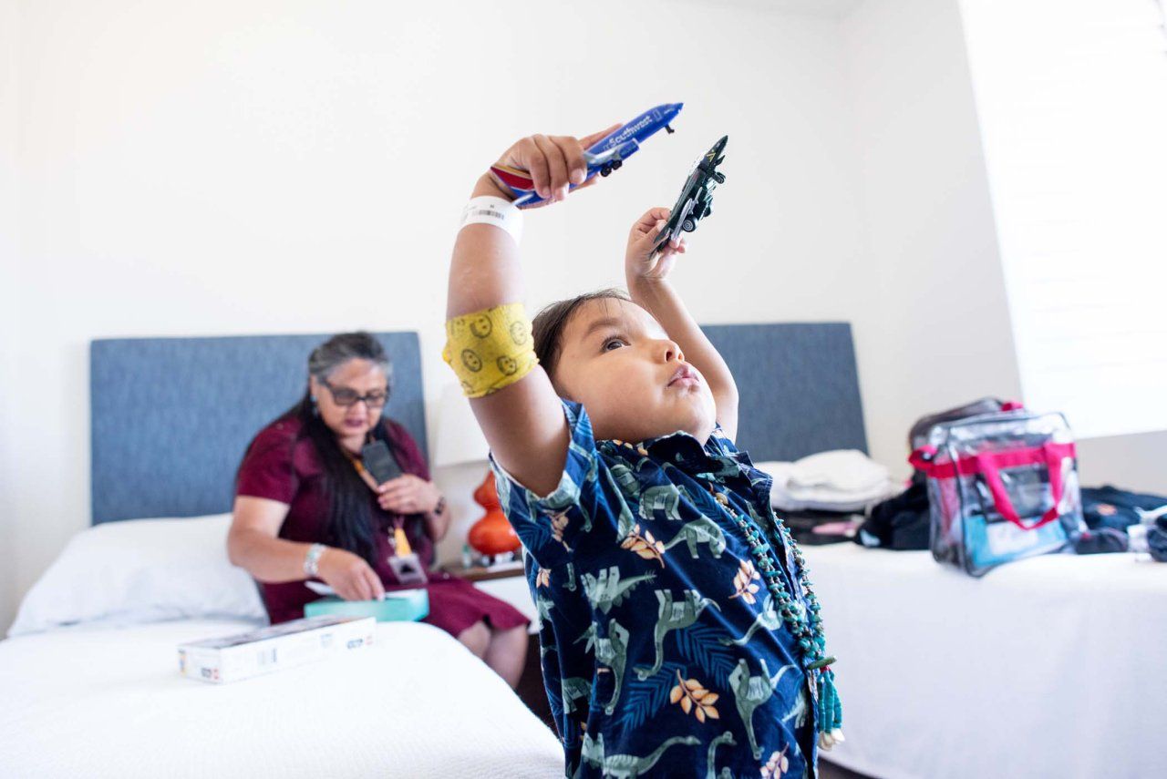 HT plays with toy airplanes while Laverna Shorty, his grandmother, sits out of focus behind