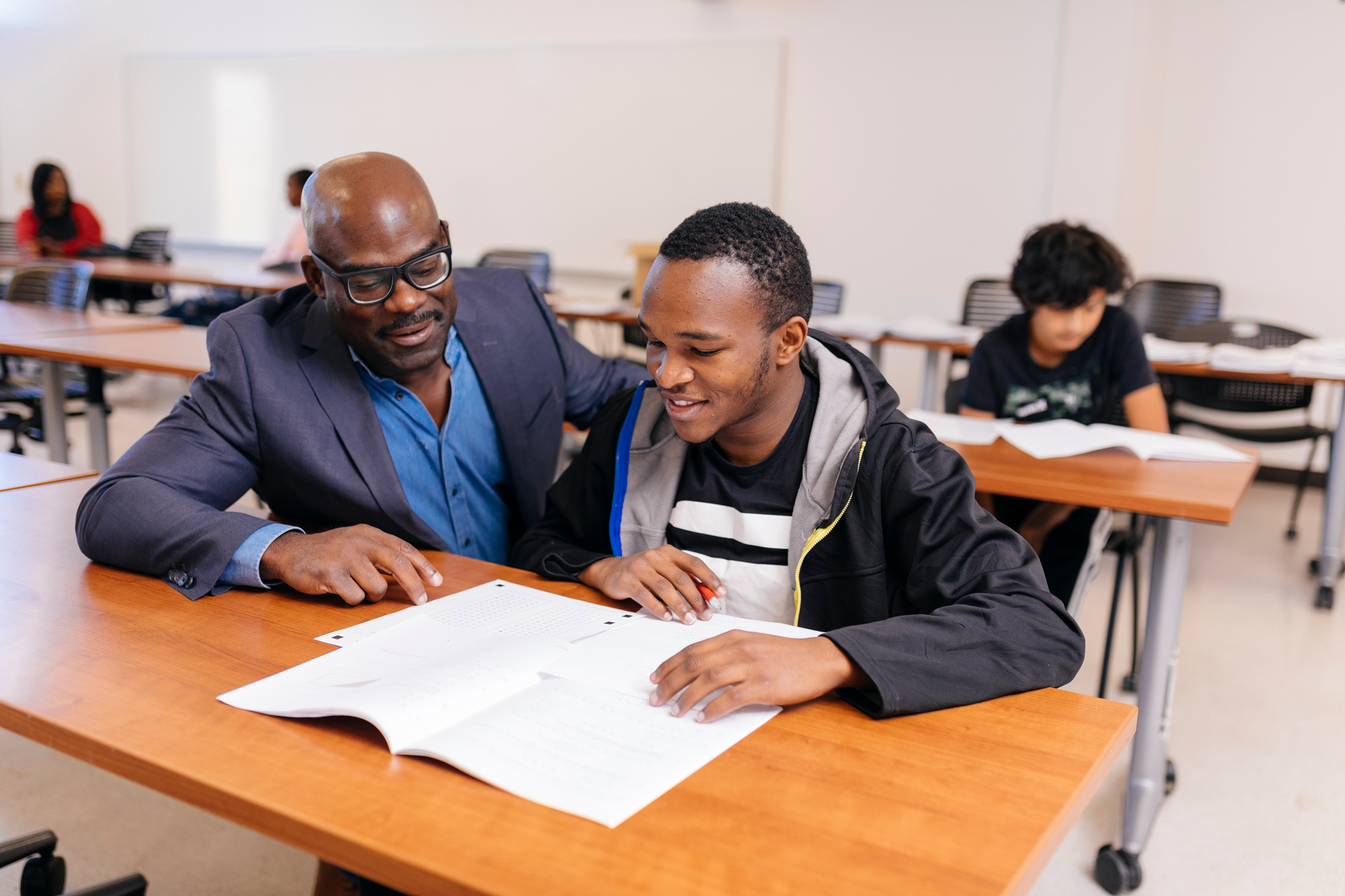 Chuck Moore helps a student with his test at his desk