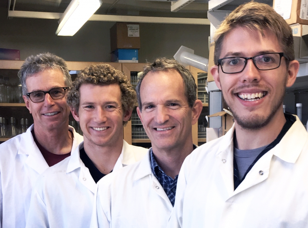 Four men in white lab coats