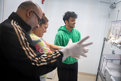 Trainees with the Nano3 veterans’ workforce training program suit up with their undergraduate teaching assistant, Margish Chodvadiya (right, in green).