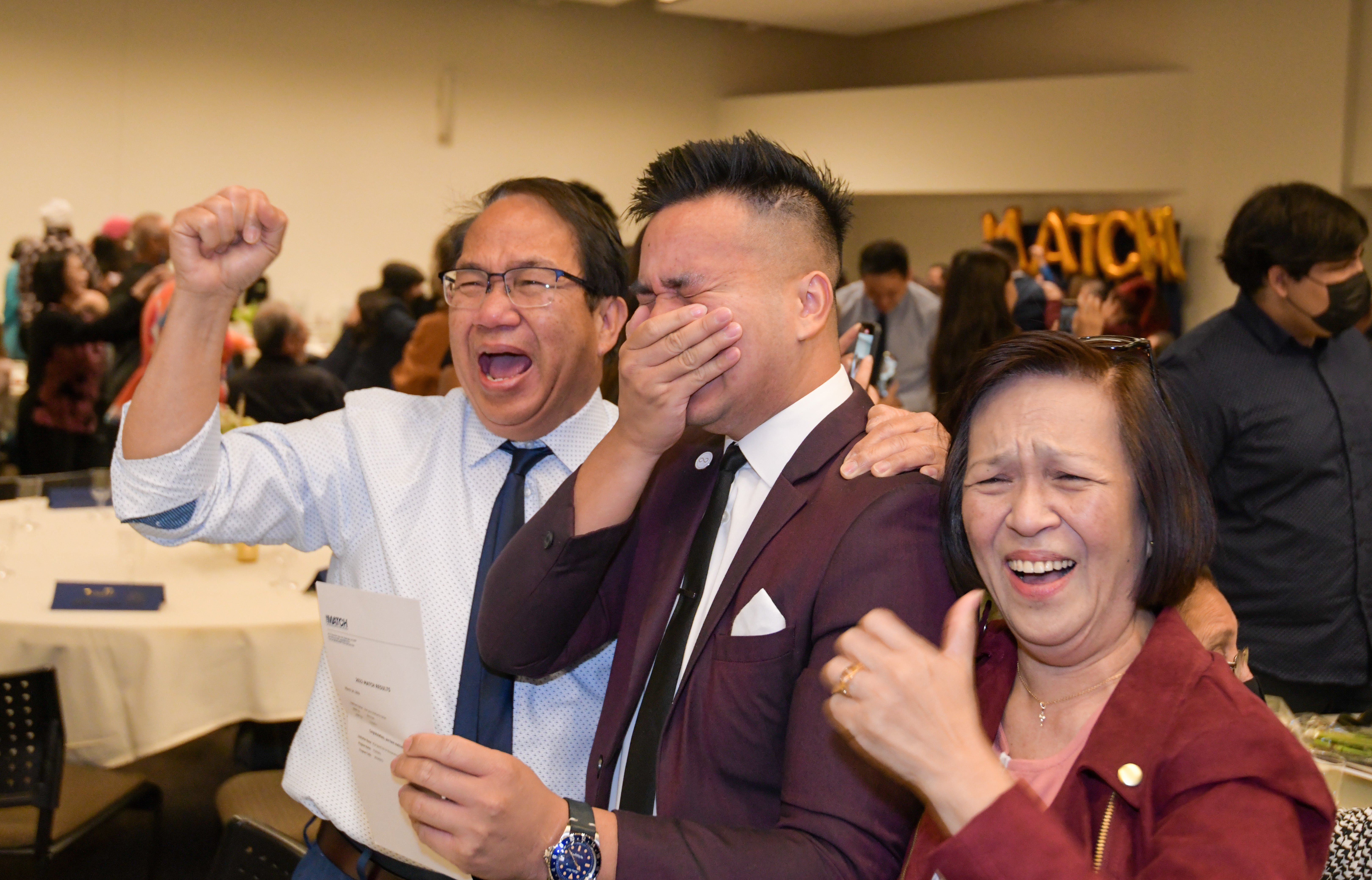 UC Riverside student holds hand over mouth in excitement, flanked by parents on Match Day