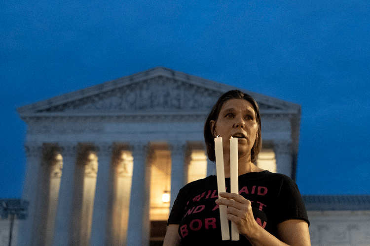 A woman holds two candles outside SCOTUS building