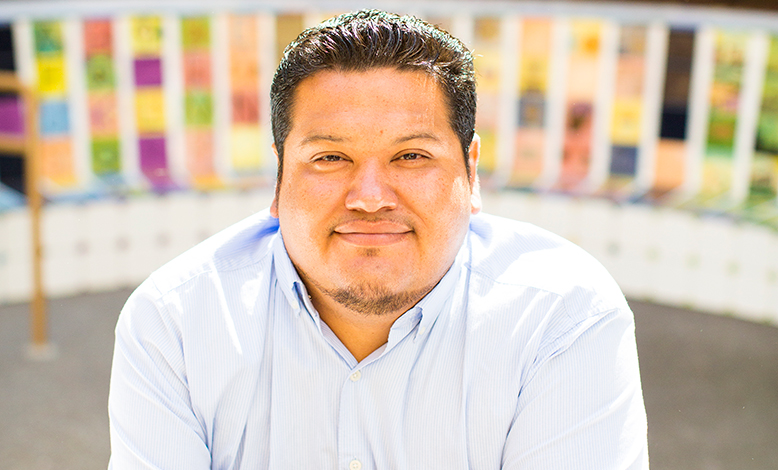 Hispanic man smiling at camera with colorful background in back