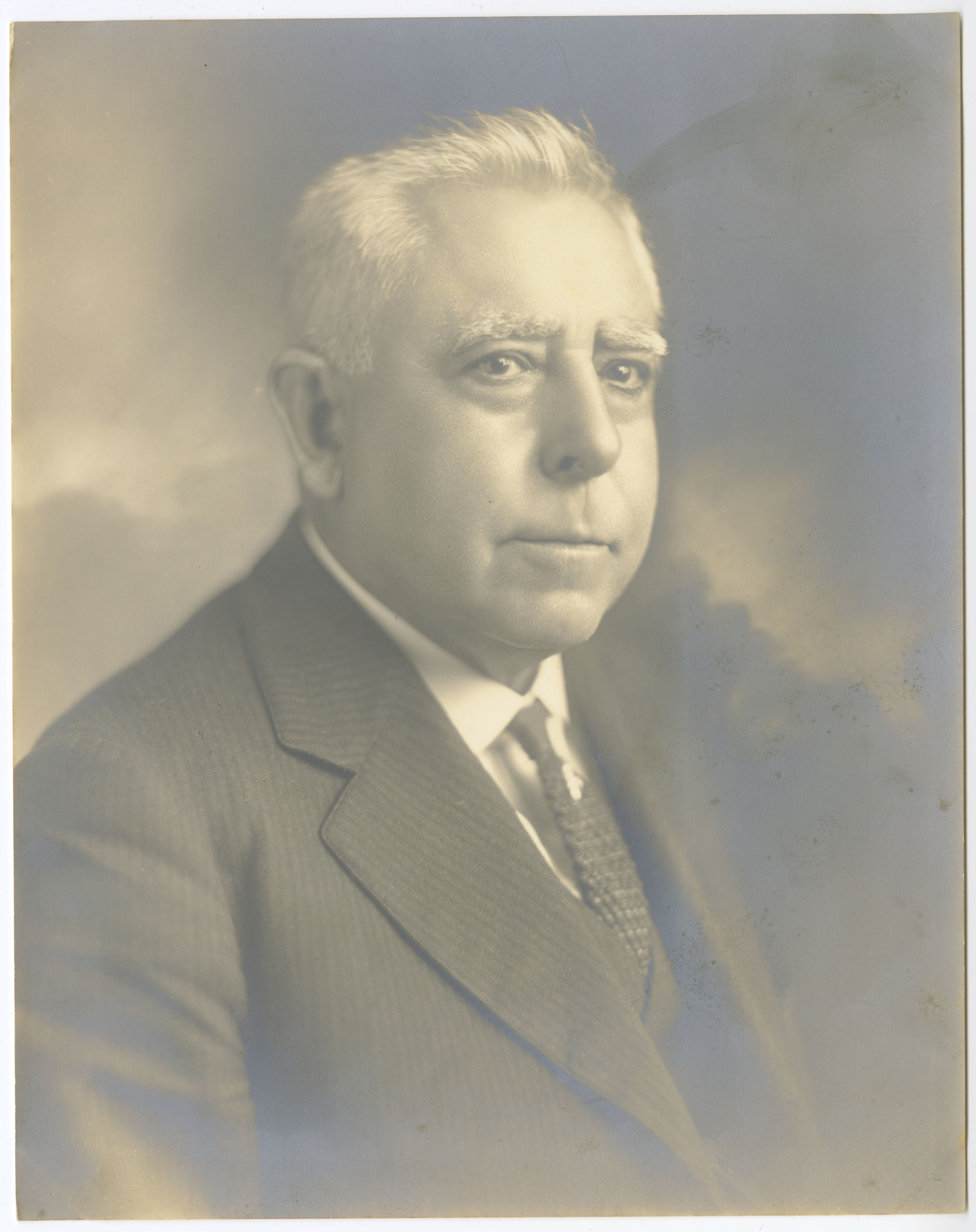 Vintage black-and-white portrait of a white haired man in a suit and tie