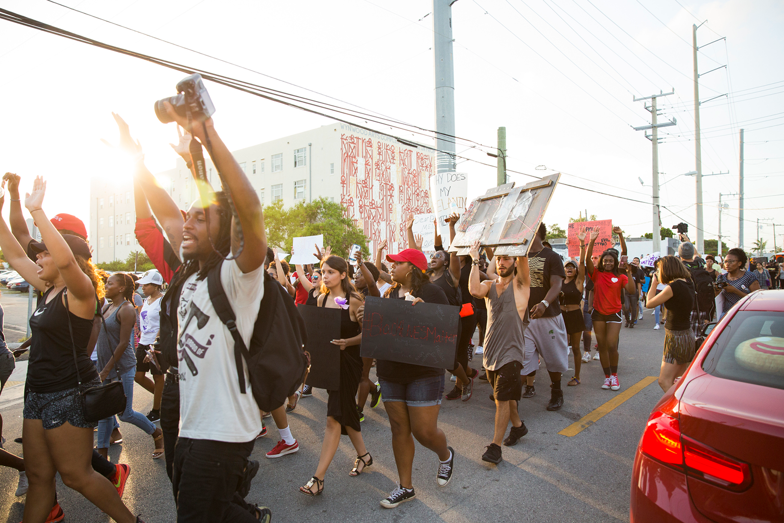A racially diverse group of young people marches on a street carrying signs with fists raised in the air