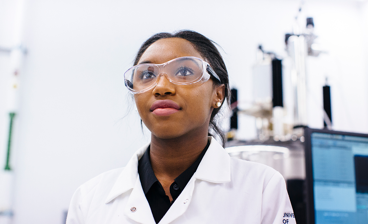 Young Black woman in lab coat and protective goggles