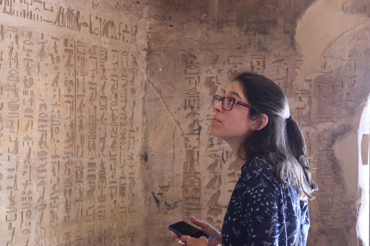 a person looking at a wall of hieroglyphics
