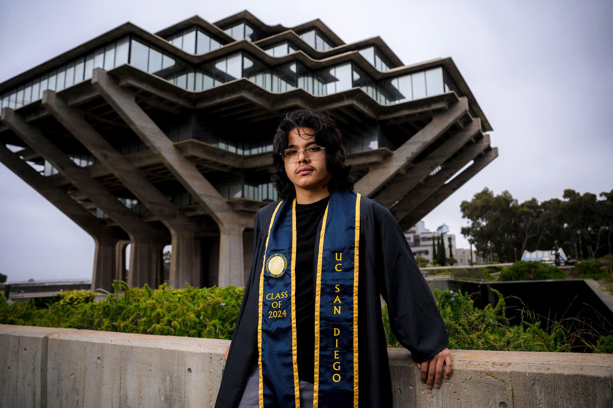 A graduate wears his gown in front of the UC San Diego library