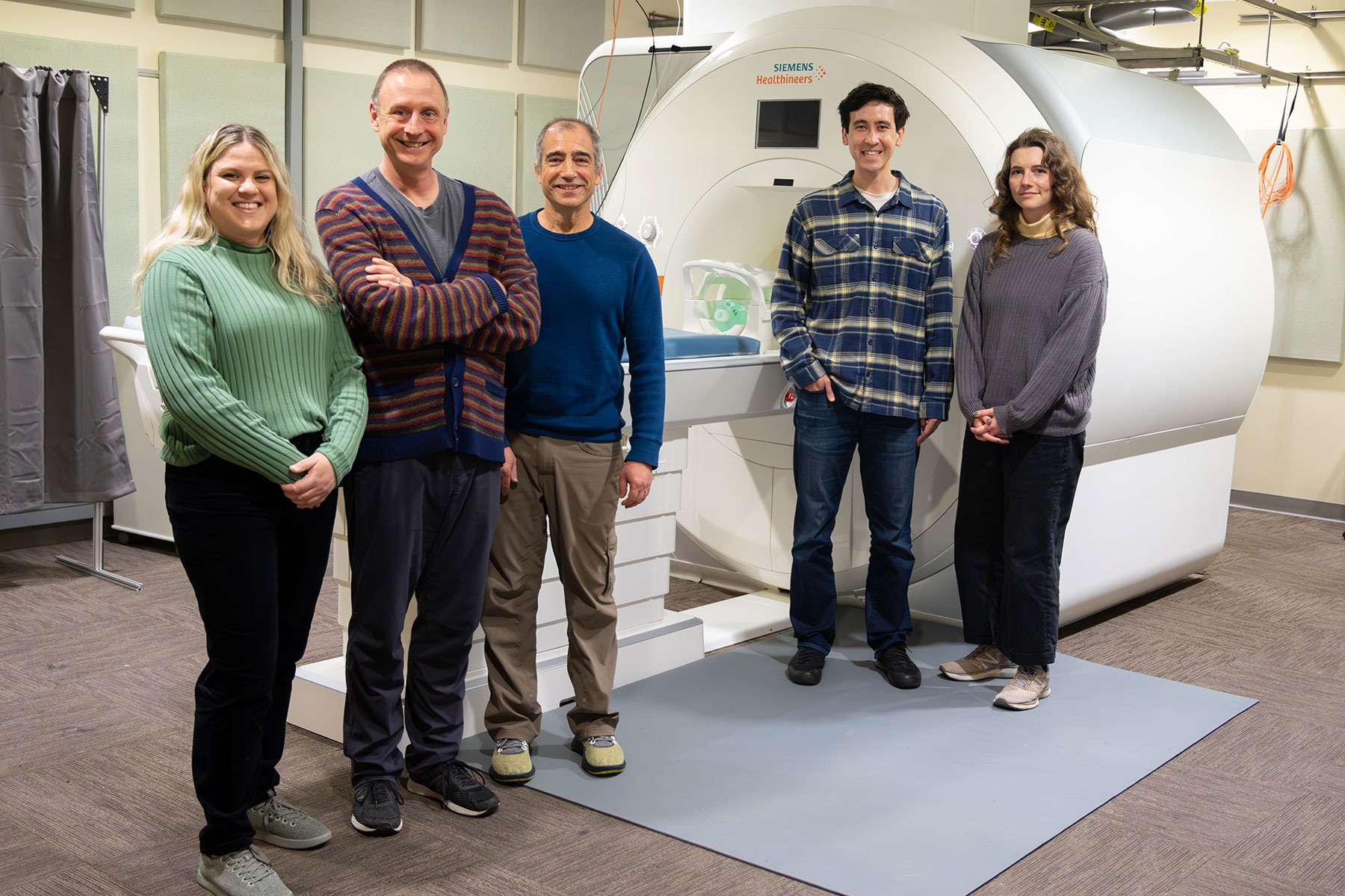 Five people stand in front of an MRI machine