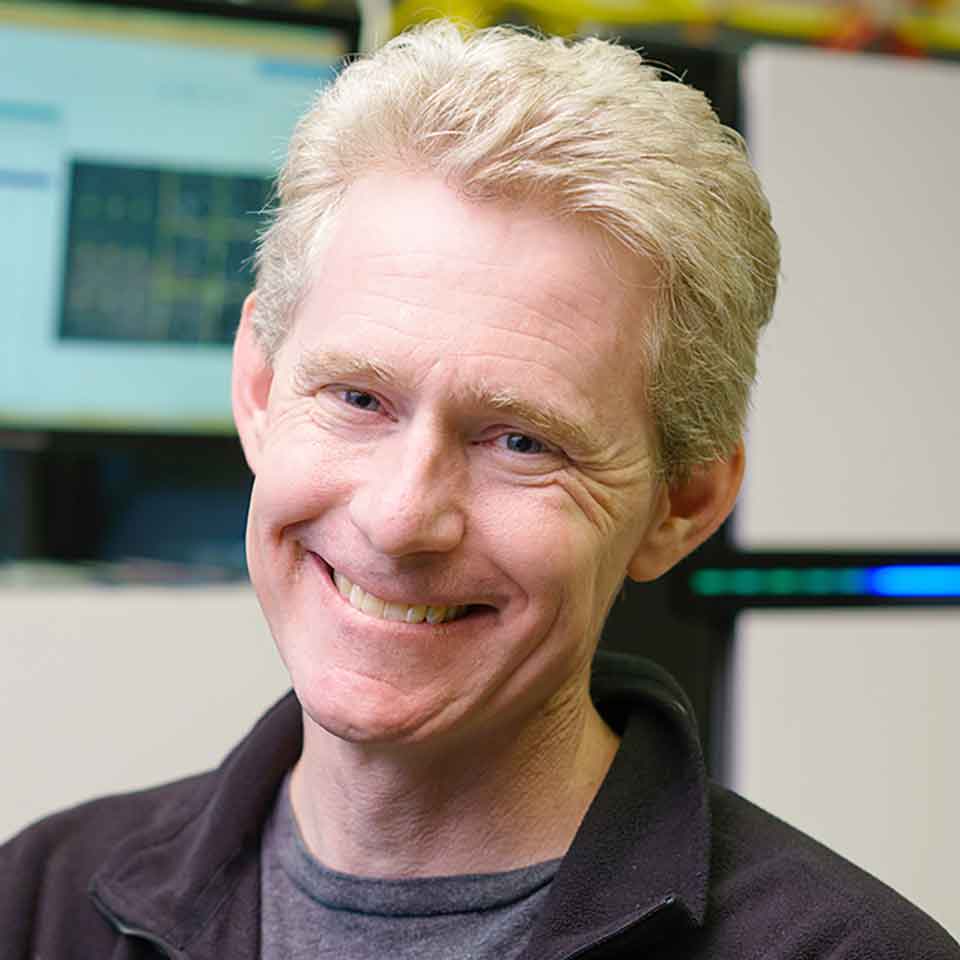 Man with blonde-whitish air smiles at camera