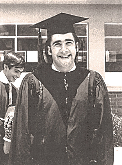 Julio Frenk as a young man with sideburns at a high school graduation, with cap and gown in a black and white photo from the 70s