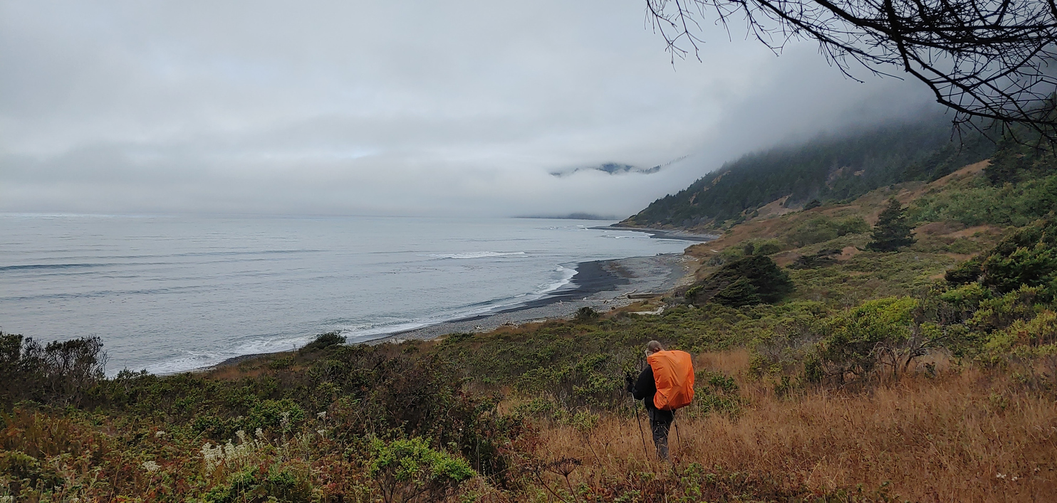 Hiker approaches a big beach on a cloudy day