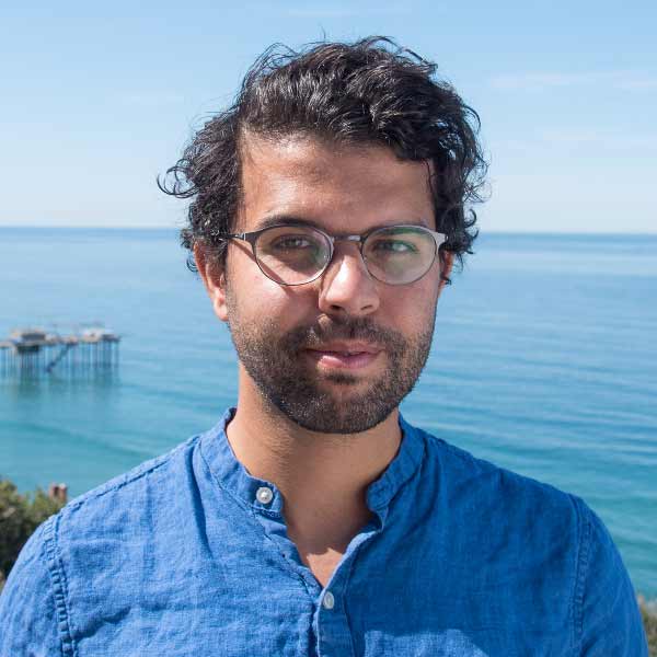 Tarik Benmarhnia in a shoulders-up portrait with the ocean in the background