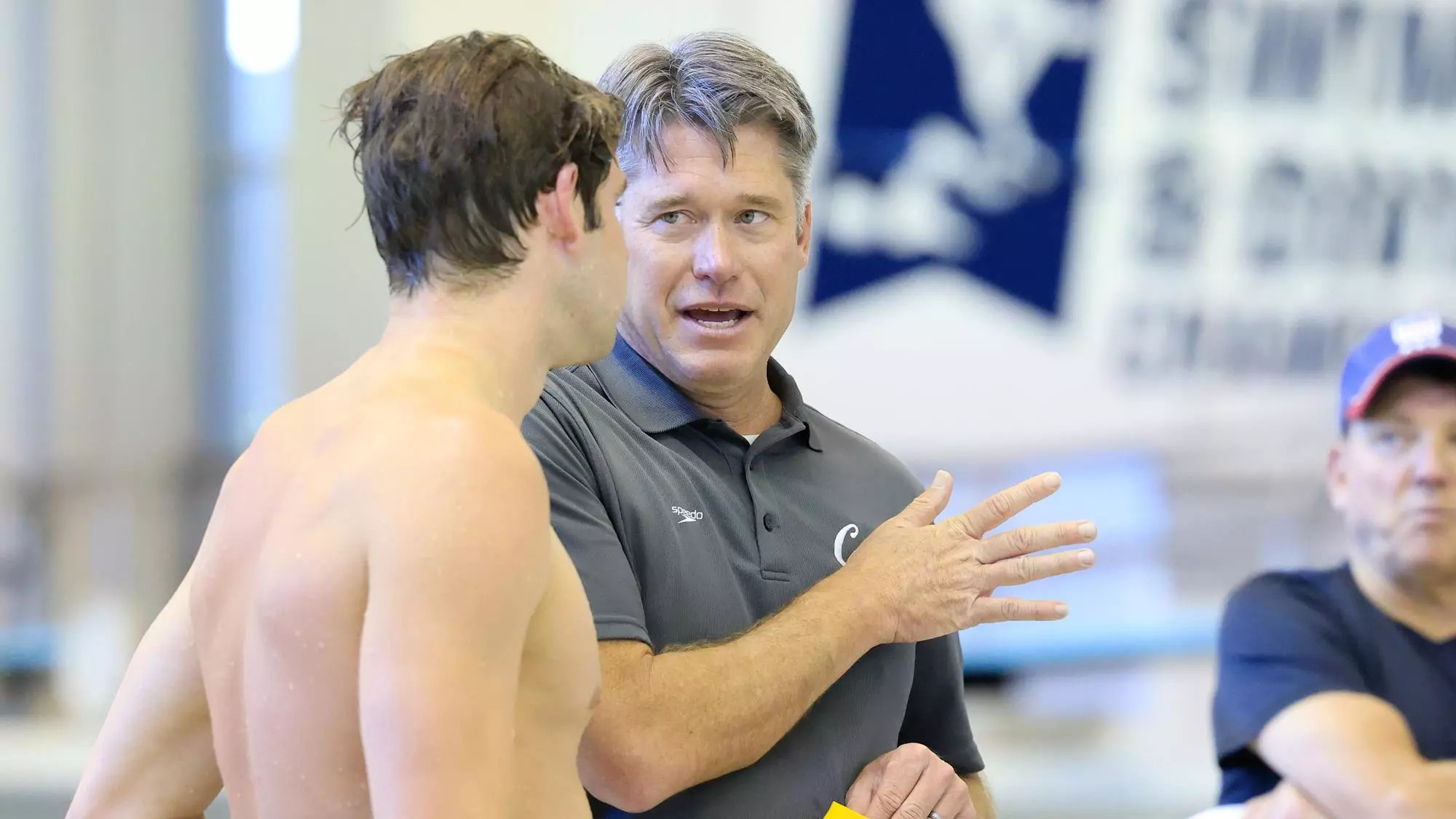 A young male swimmer, left, listens to a man with gray hair, gesturing -- Dave Durden with Ryan Murphy