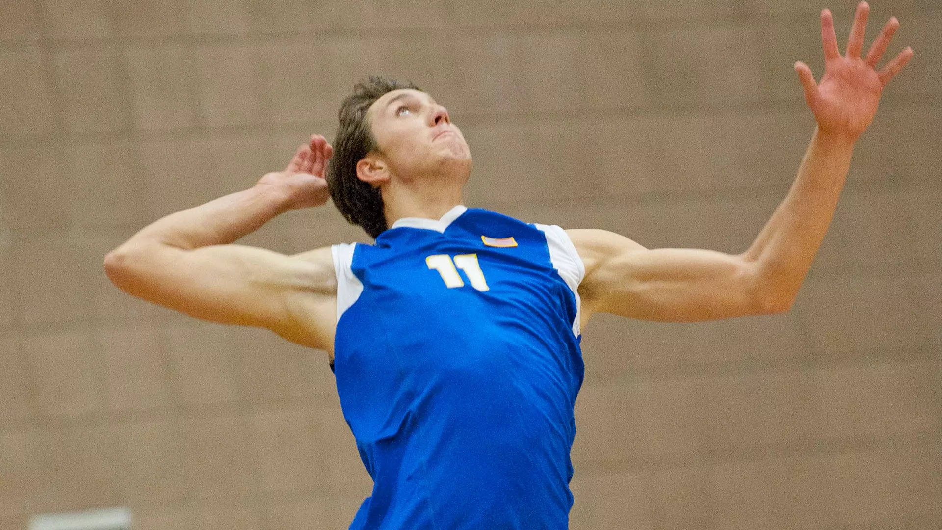 Young man with dark hair prepares to hit a volleyball