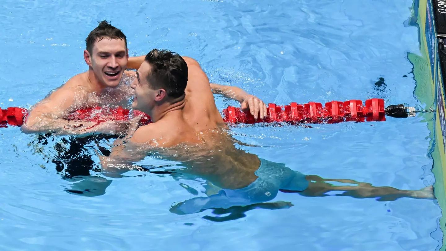 Two male swimmers talk across the lane after a race