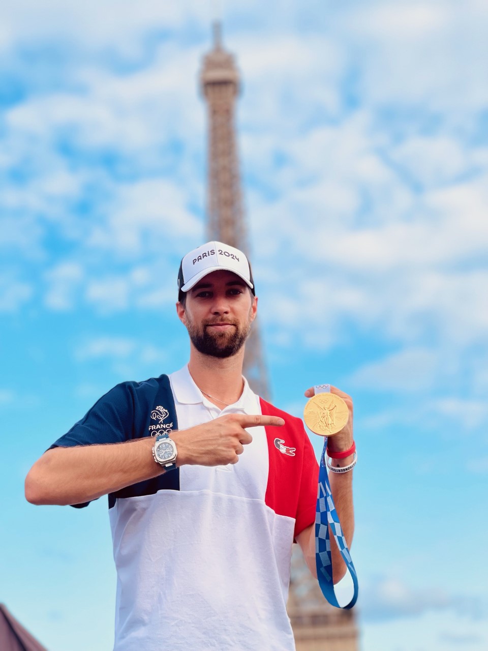 Man with beard and a cap holds up his gold medal in front of the Eiffel Tower -- Kévin Tillie courtesy photo