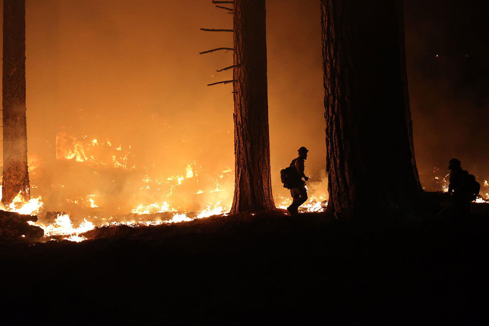 A silhouette of a firefighter battling flames at night