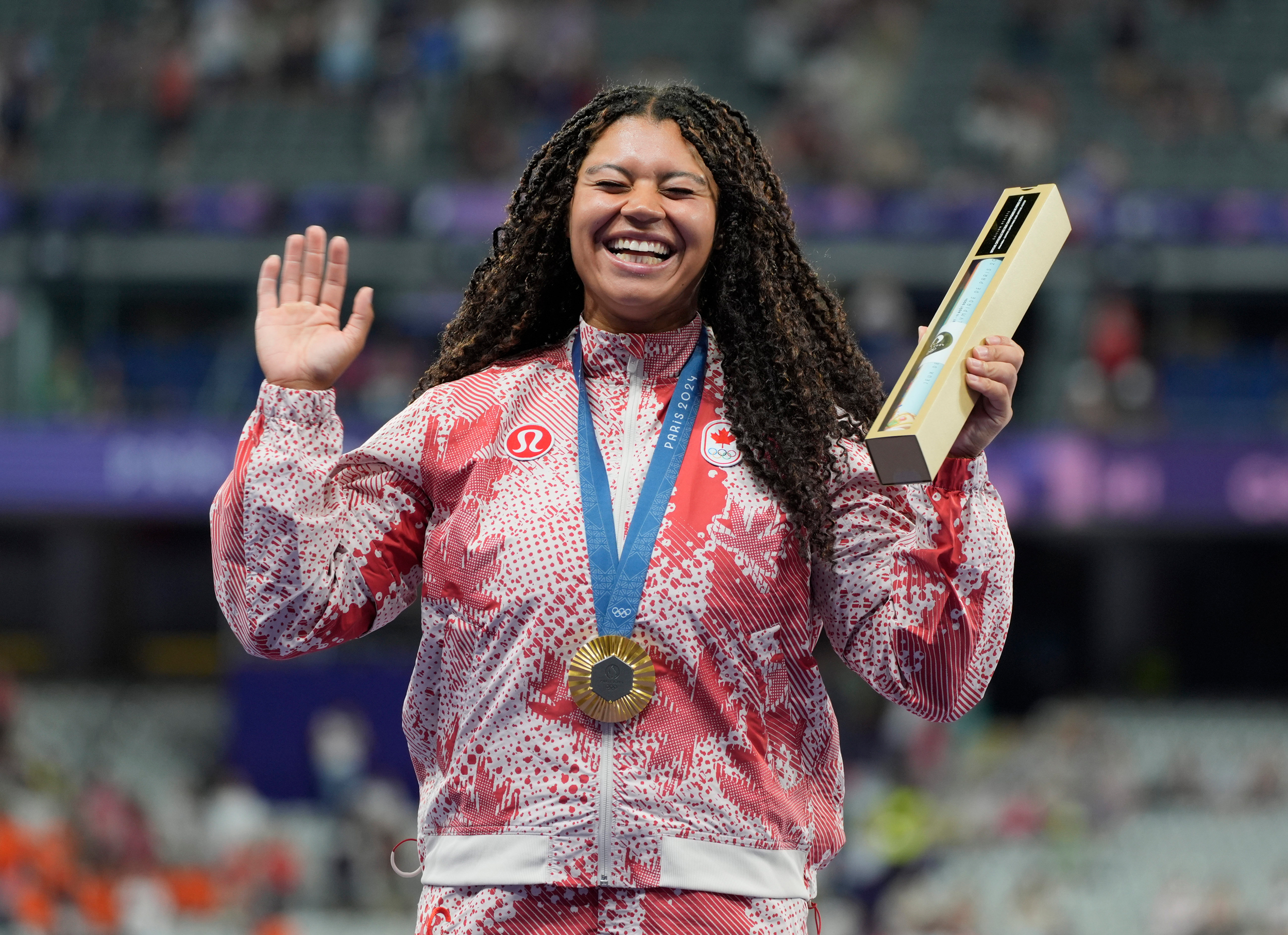 Camryn Rogers, a young Black woman in a Canadian tracksuit wearing a gold medal, hands in the air, overcome with emotion © Andrew Nelles-USA TODAY Sports