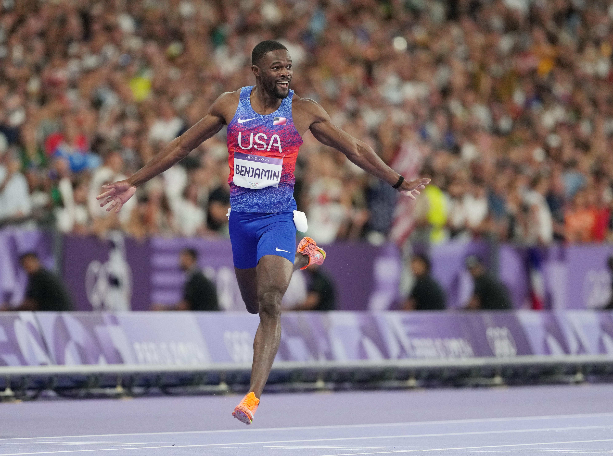 Rai Benjamin in USA uniform grinning in full stride after crossing the finish line in the 400 meter hurdles © James Lang-USA TODAY Sports 