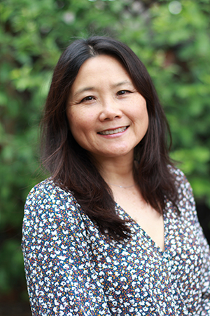 Woman with long black hair smiles at camera -- June Yu headshot