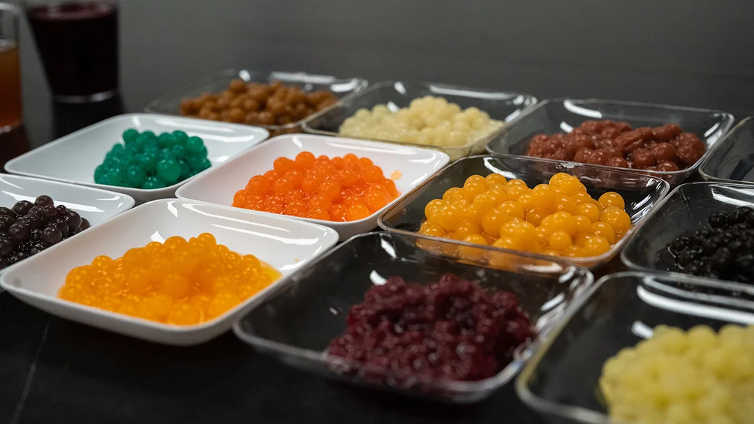 Colorful spherical food in little bins (different colors in each bin)