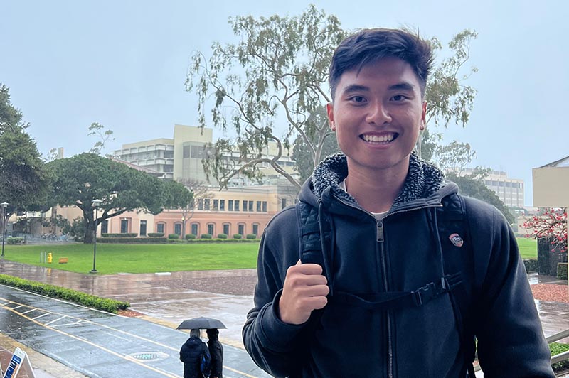 Smiling young man at UC Santa Barbara on a rainy day