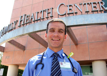 Charles Vega wearing a stethescope around his neck, standing in front of the Family Medicine Health Center at UCI