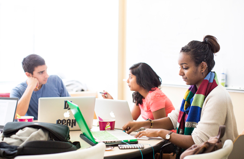 Students talking and working together on laptops at a table