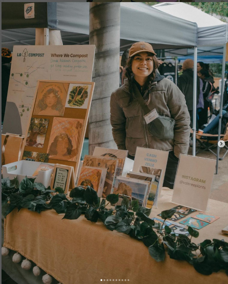 Valeree Catangay smiles at a booth with her art displayed in front of it