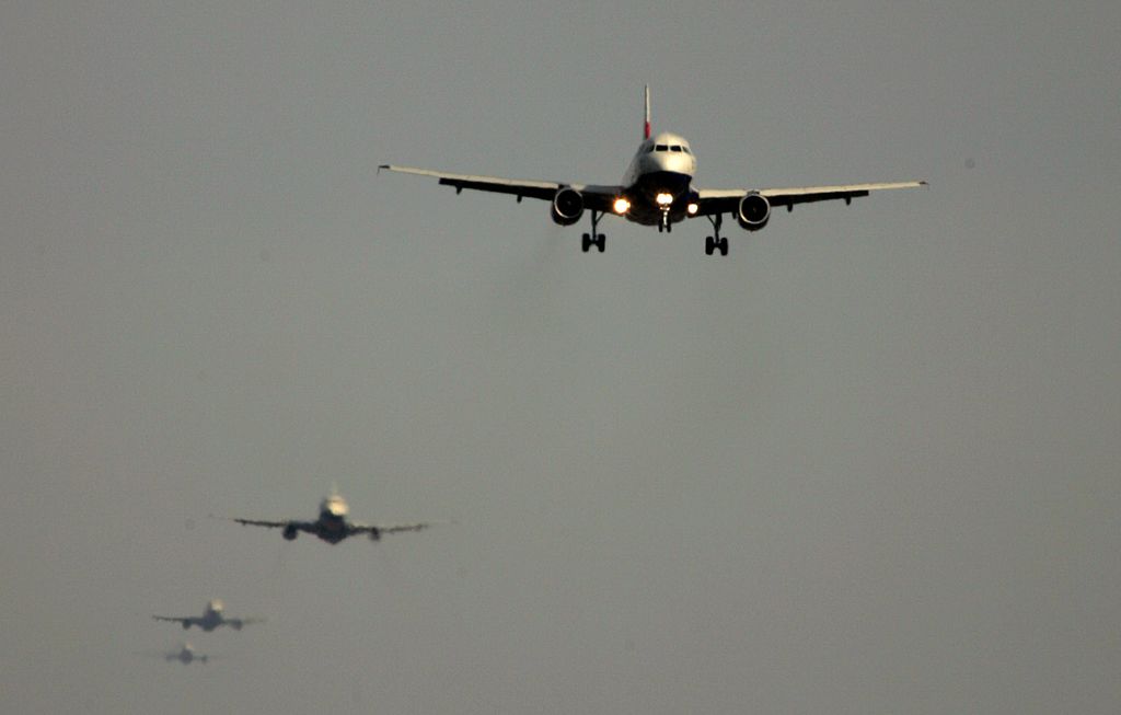 Four jets fly in a line toward the camera, approaching an airport