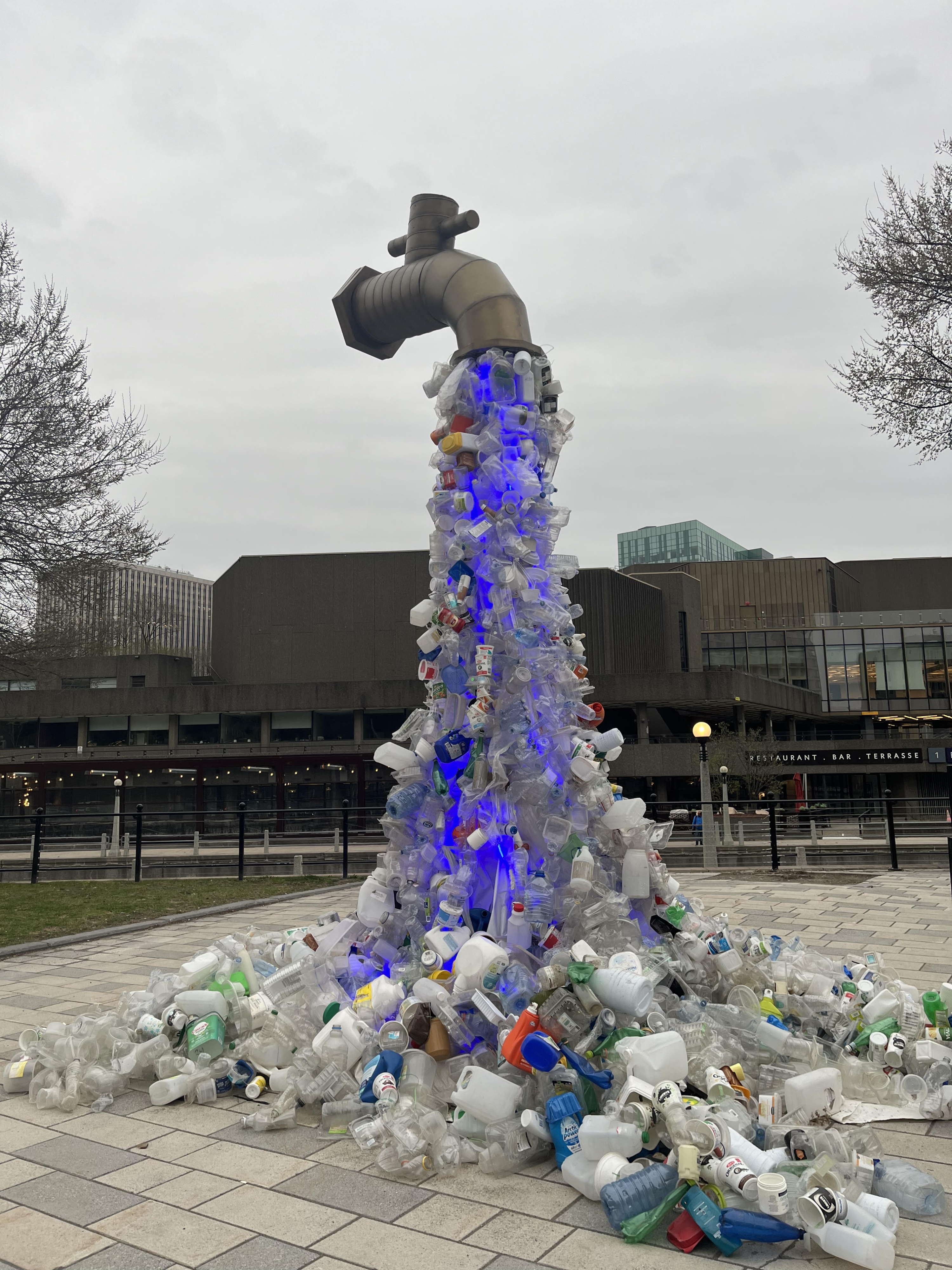 A statute of a freestanding tap at the top of a pile of plastics