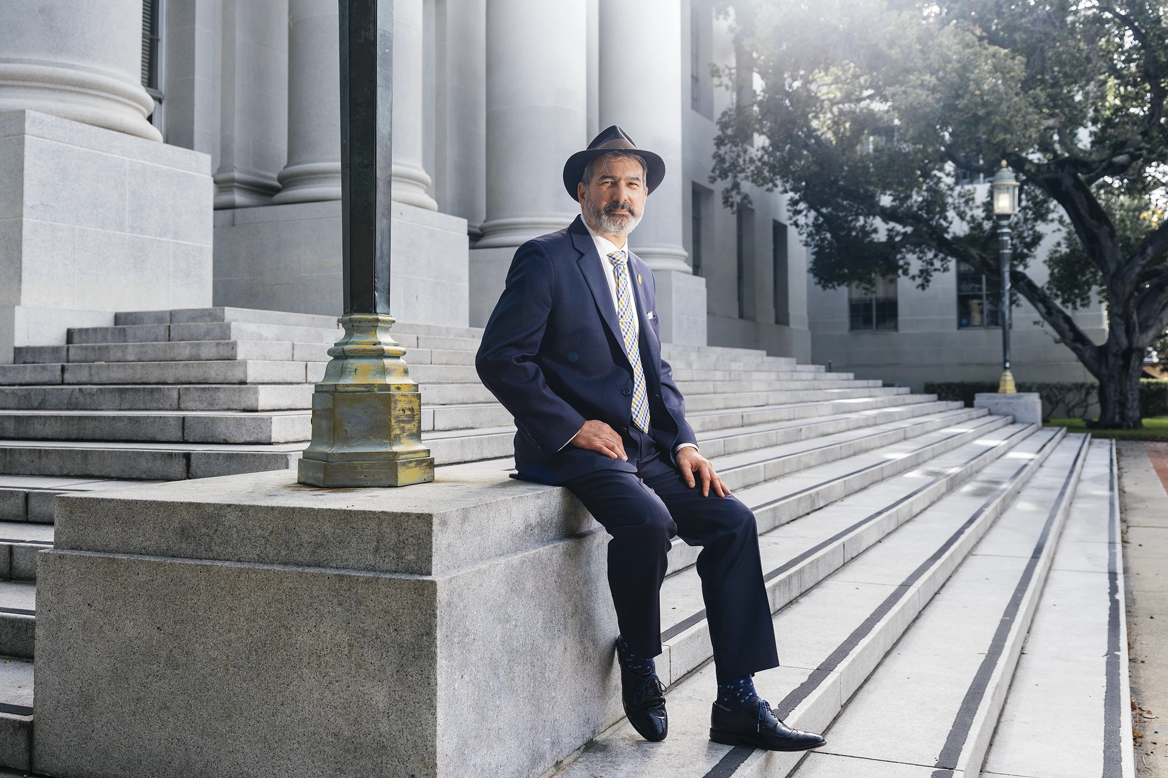 A bearded man in a suit and a hat sits on the marble steps of a building (Mark A. Lawson)