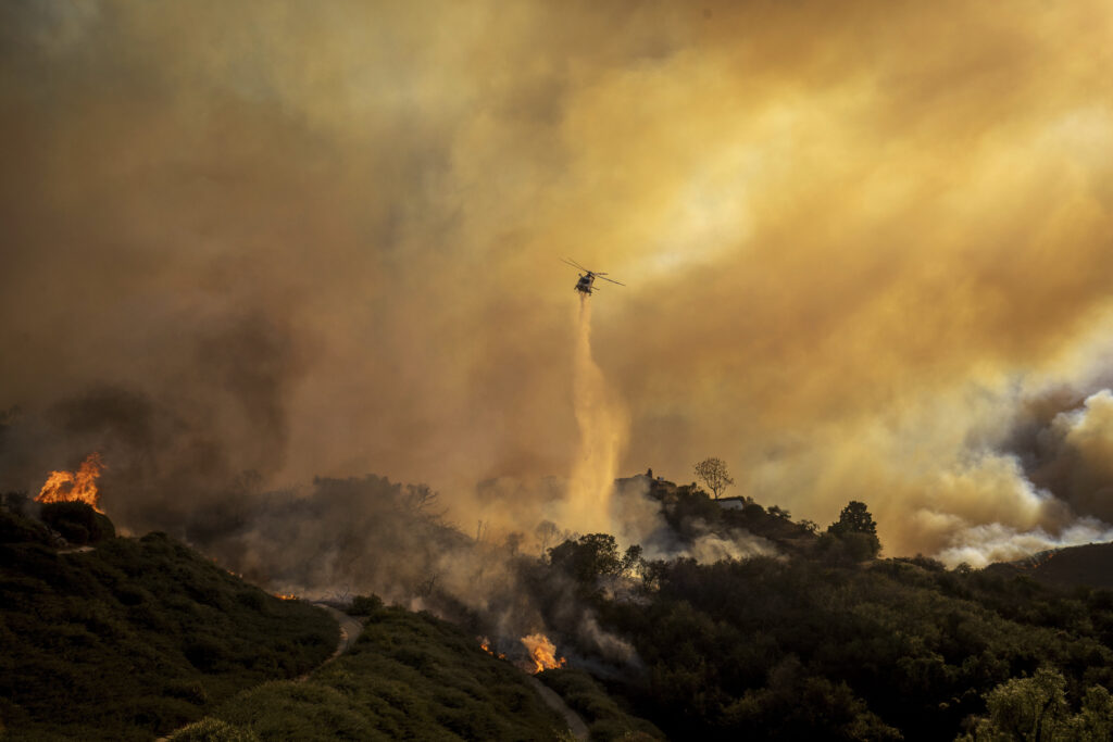 Water is dropped on the advancing Palisades Fire by helicopter in the Pacific Palisades neighborhood of Los Angeles.