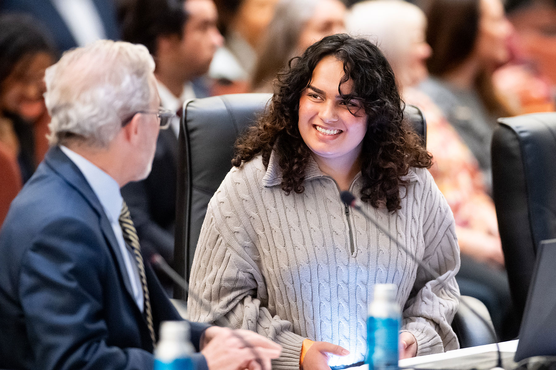 Alishba Sardar sets at a dais next to UC Berkeley Chancellor Rich Lyons, smiling