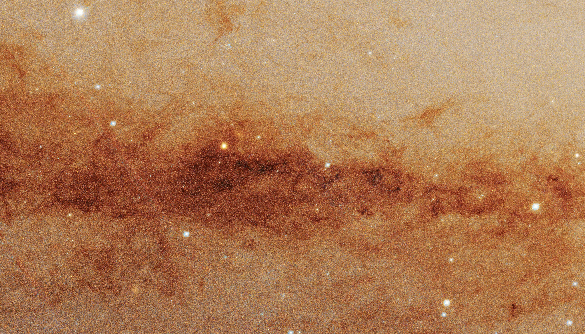 A part of the Andromeda galaxy that in the image looks beige with soft red streaks of dust 