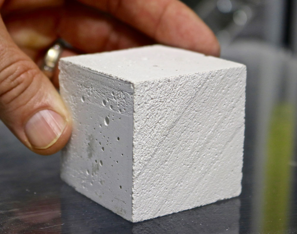 A hand holding a block of CO2NCRETE